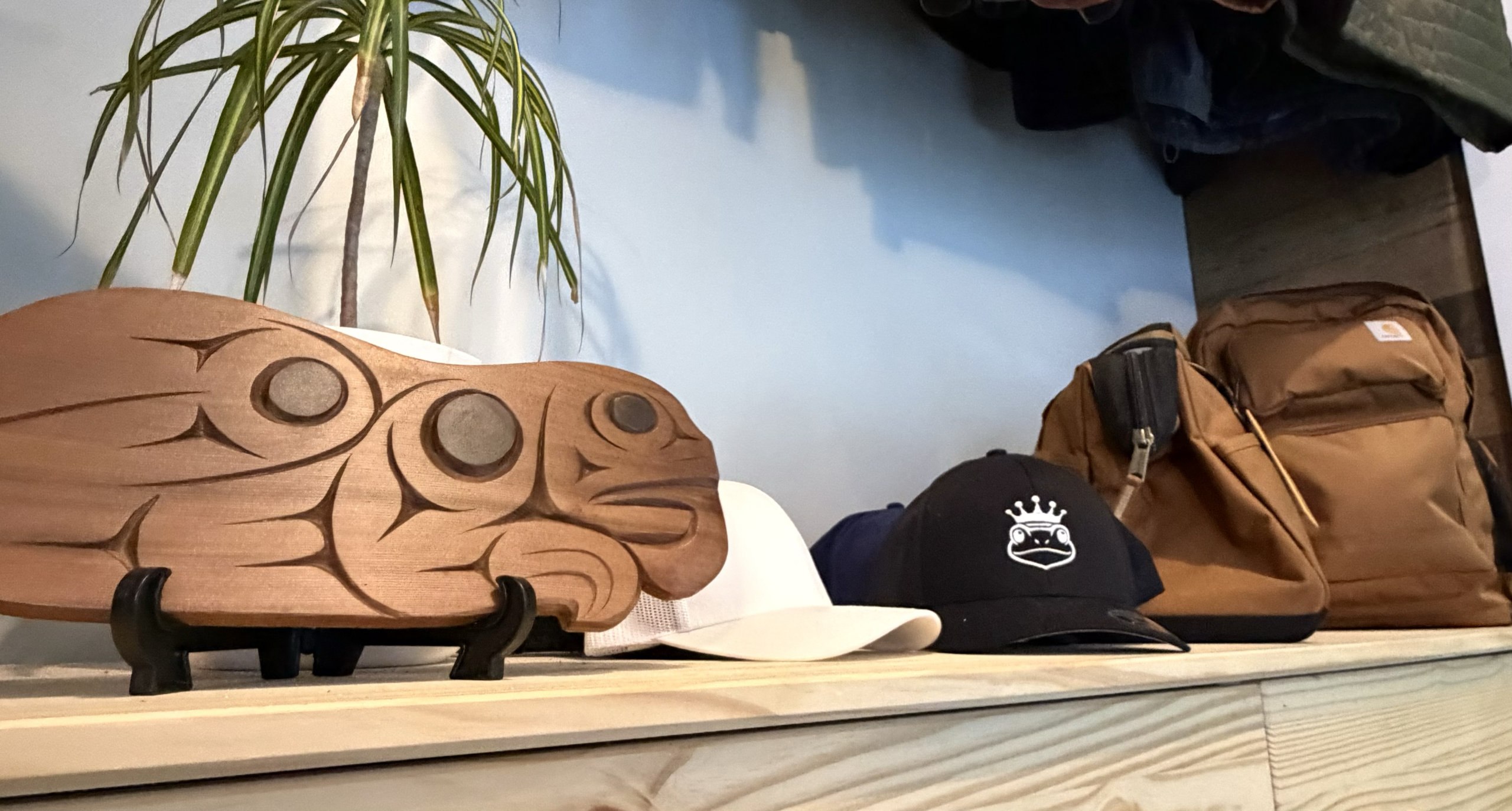 Bad Frog shop shelf — carved frog art, embroidered caps, and branded bags